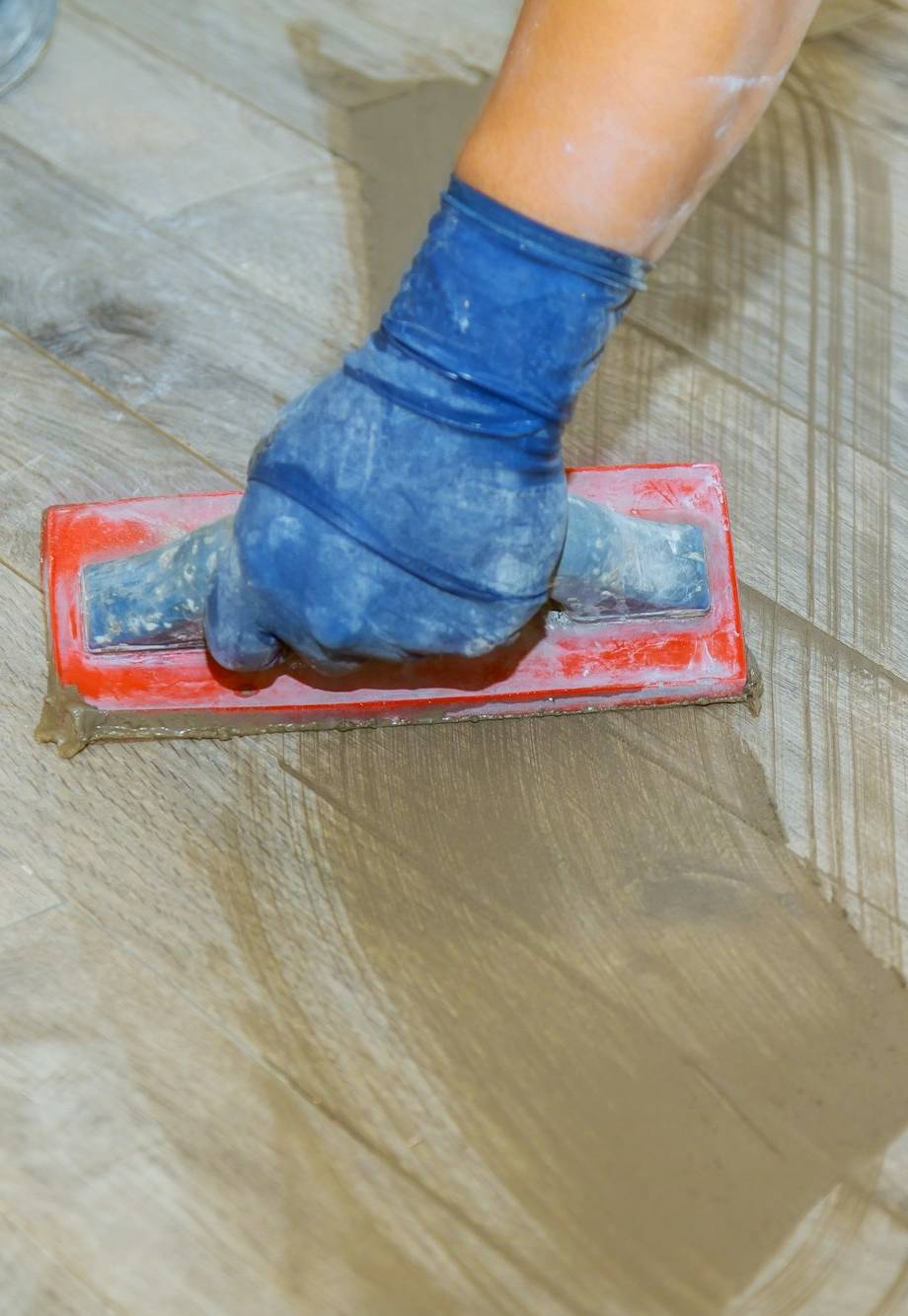 Hand of flooring on gray color of new grout tile on tile gray for the final step for flooring